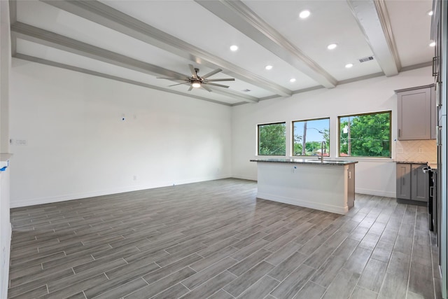 kitchen featuring ceiling fan, hardwood / wood-style floors, a center island, and beamed ceiling