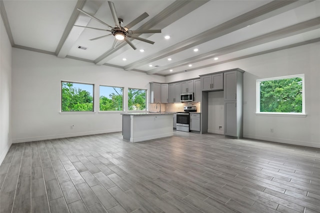 kitchen featuring light stone countertops, a center island, stainless steel appliances, gray cabinets, and light wood-type flooring