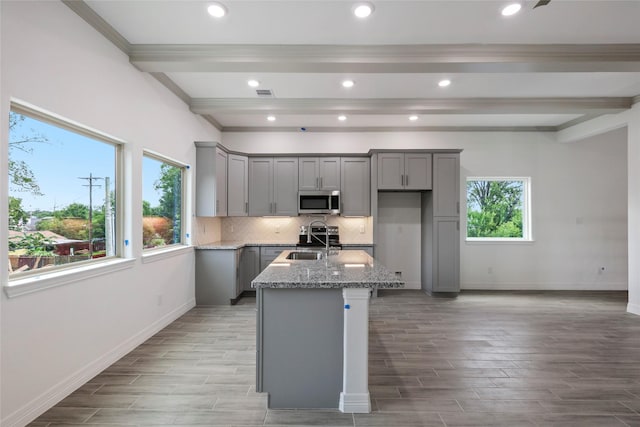 kitchen with gray cabinetry, light stone counters, and a wealth of natural light