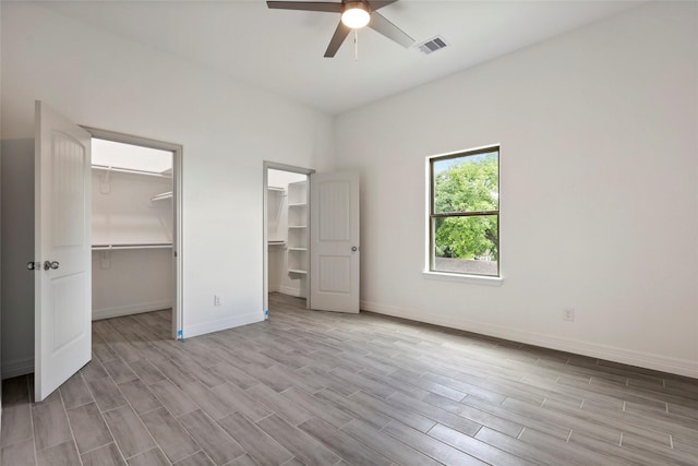 unfurnished bedroom with ceiling fan, light hardwood / wood-style flooring, and a spacious closet