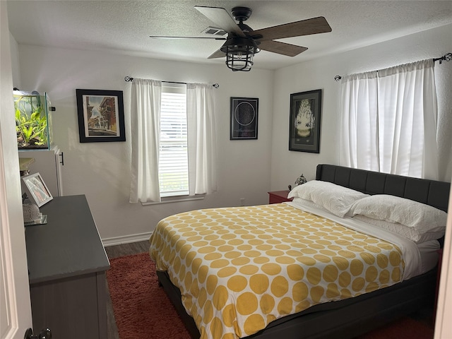 bedroom featuring hardwood / wood-style floors, ceiling fan, and a textured ceiling