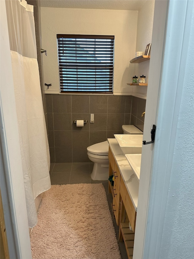 bathroom featuring toilet, vanity, tile patterned floors, and tile walls