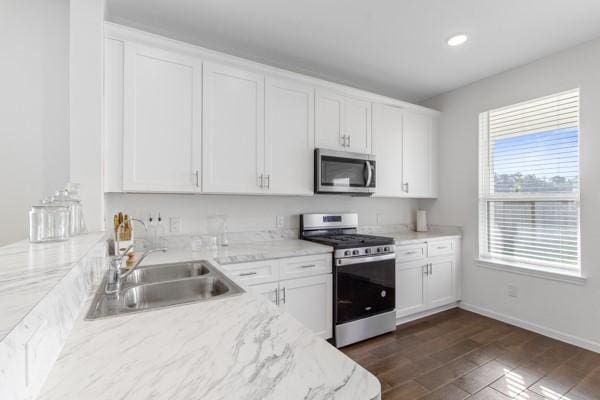 kitchen featuring light stone countertops, stainless steel appliances, sink, dark hardwood / wood-style floors, and white cabinetry