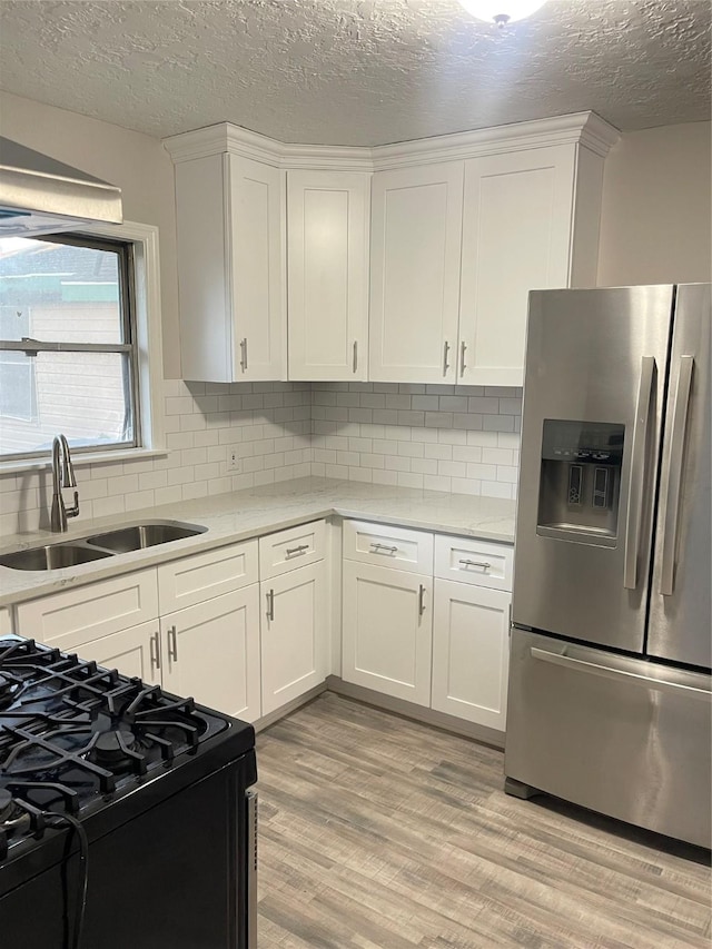 kitchen with white cabinetry, stainless steel fridge, sink, and black range