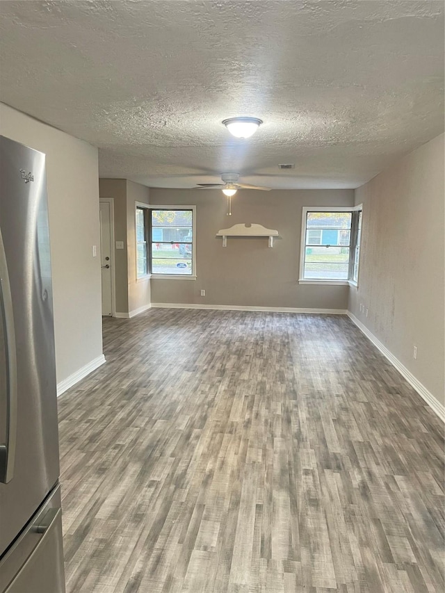 unfurnished living room featuring hardwood / wood-style floors, a textured ceiling, ceiling fan, and a healthy amount of sunlight