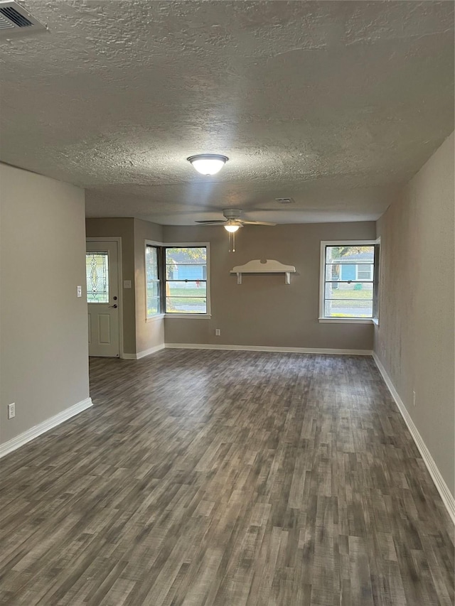 spare room featuring a textured ceiling, dark wood-type flooring, and a wealth of natural light