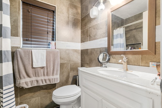 bathroom with vanity, toilet, and tile walls