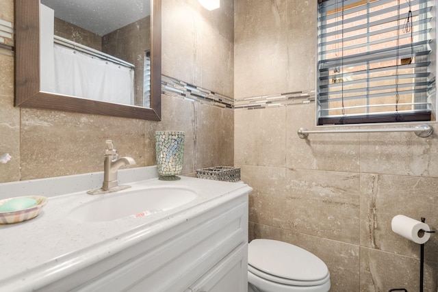 bathroom with vanity, tile walls, and toilet