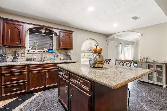 kitchen featuring a center island, backsplash, a kitchen breakfast bar, sink, and a textured ceiling