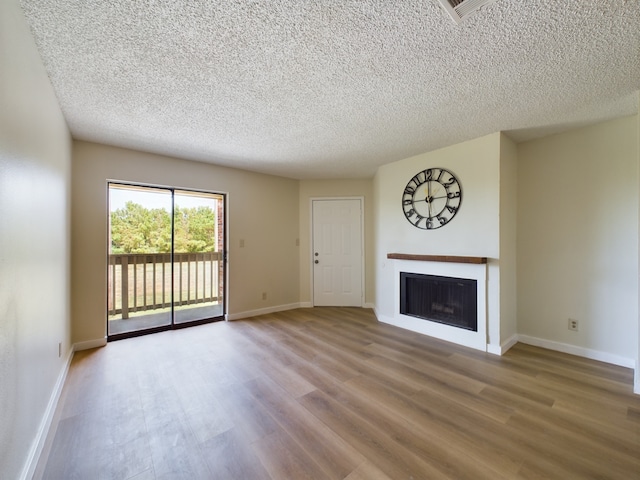 unfurnished living room featuring wood-type flooring and a textured ceiling