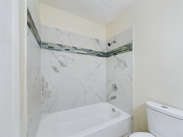 bathroom with tiled shower / bath, a textured ceiling, and toilet