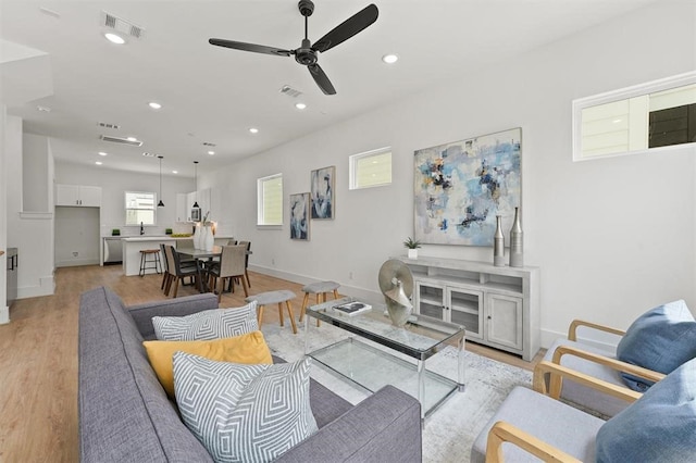 living room with plenty of natural light, light hardwood / wood-style floors, sink, and ceiling fan