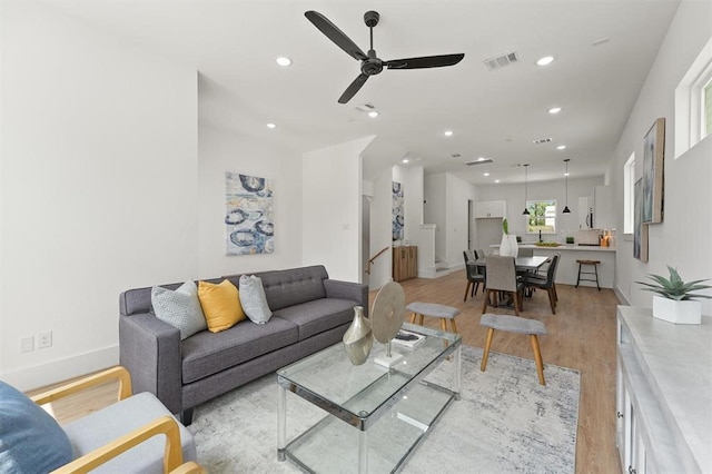 living room with ceiling fan and light hardwood / wood-style flooring