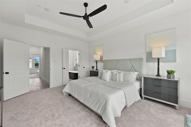 bedroom featuring a raised ceiling, ensuite bathroom, ceiling fan, and carpet