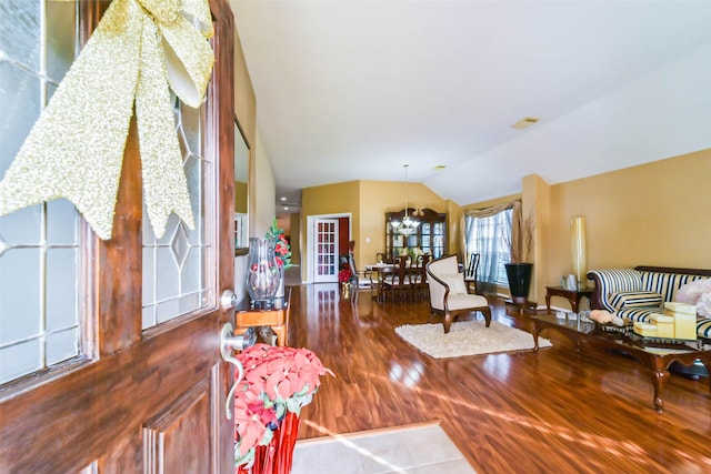 living room with hardwood / wood-style flooring, lofted ceiling, and an inviting chandelier