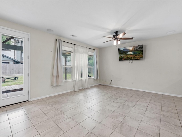 empty room with ceiling fan, a healthy amount of sunlight, and light tile patterned floors