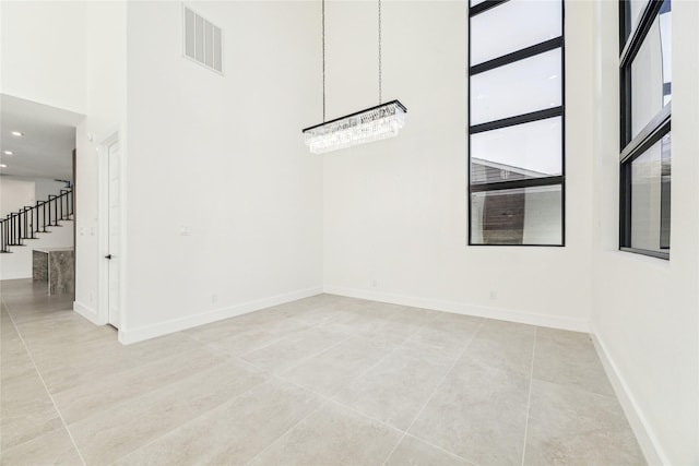 unfurnished room featuring a high ceiling, an inviting chandelier, and light tile patterned flooring