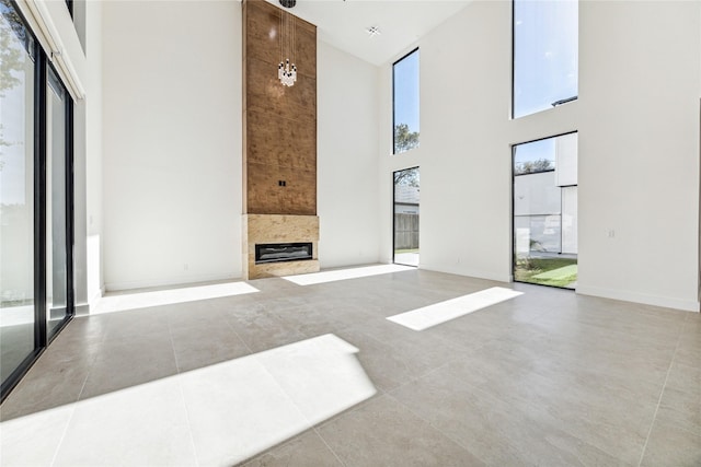 unfurnished living room featuring light tile patterned floors, a fireplace, and a high ceiling