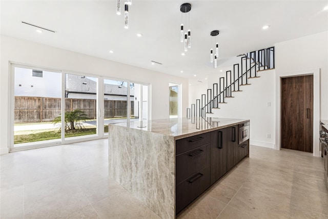 kitchen featuring dark brown cabinetry, plenty of natural light, a spacious island, and decorative light fixtures