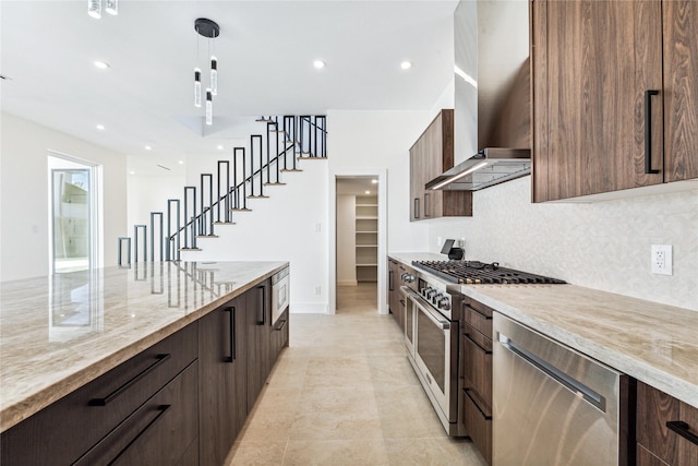 kitchen with stainless steel appliances, wall chimney range hood, light stone counters, decorative light fixtures, and decorative backsplash