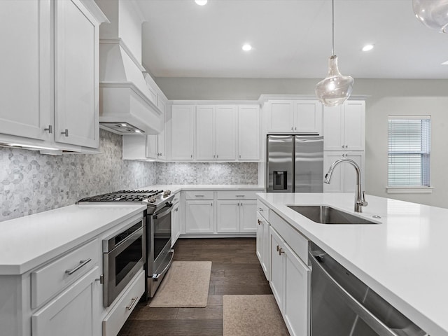 kitchen with dark hardwood / wood-style flooring, premium range hood, stainless steel appliances, sink, and decorative light fixtures