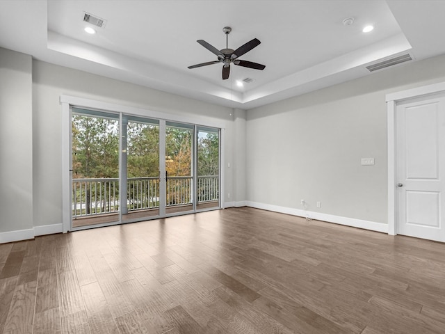 spare room with wood-type flooring, a raised ceiling, and ceiling fan