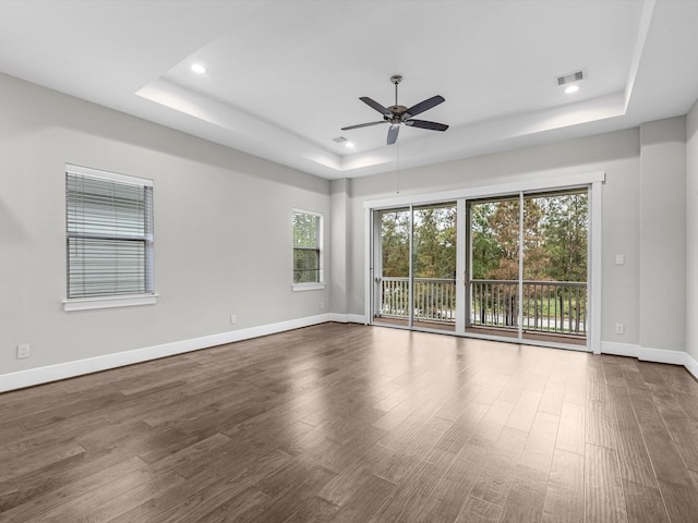 unfurnished room featuring hardwood / wood-style flooring, ceiling fan, and a tray ceiling