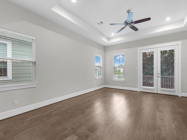 spare room with a tray ceiling, french doors, and dark wood-type flooring