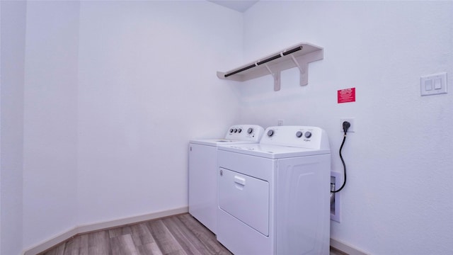 laundry area featuring washing machine and dryer and light hardwood / wood-style floors