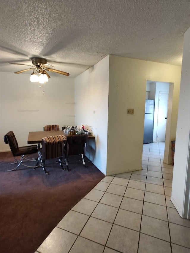 tiled dining area featuring ceiling fan and a textured ceiling