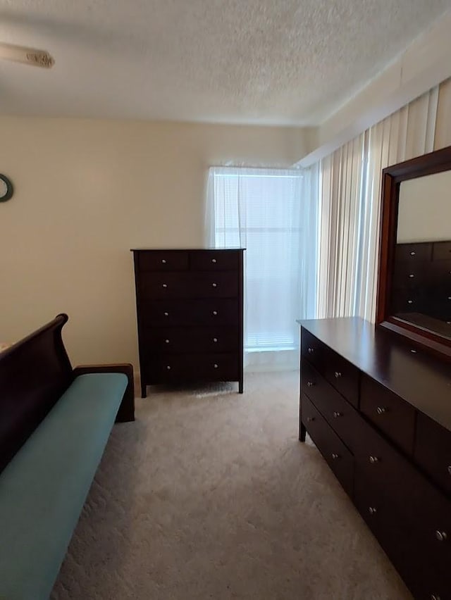 bedroom with a textured ceiling and light carpet