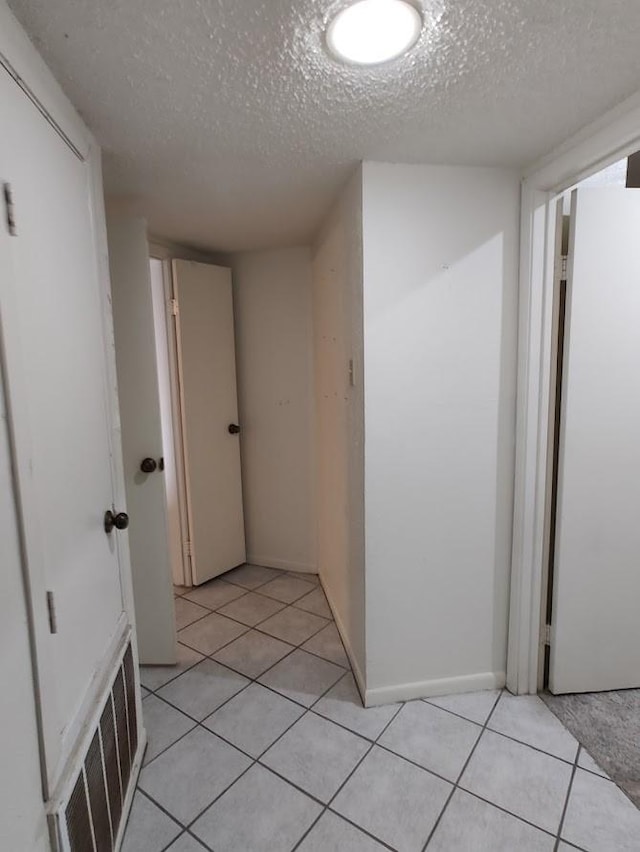 hallway featuring light tile patterned flooring and a textured ceiling