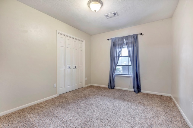 unfurnished bedroom featuring carpet, a textured ceiling, and a closet