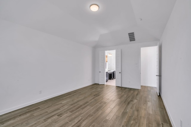 unfurnished room featuring vaulted ceiling and hardwood / wood-style floors