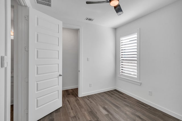 unfurnished bedroom featuring dark wood-type flooring, ceiling fan, a walk in closet, and a closet