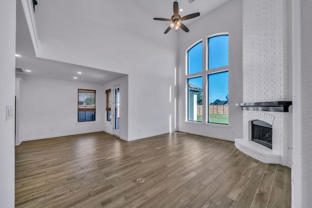 unfurnished living room with ceiling fan and a brick fireplace