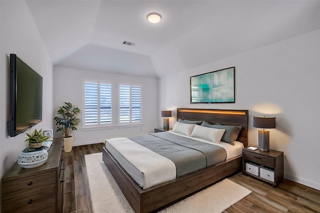 bedroom with dark wood-type flooring and lofted ceiling