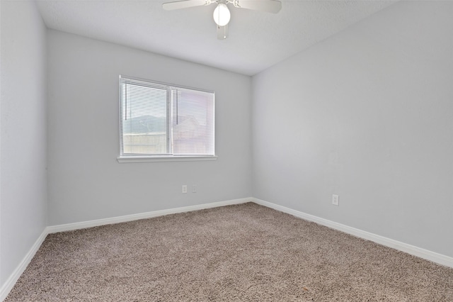 carpeted empty room with a ceiling fan and baseboards