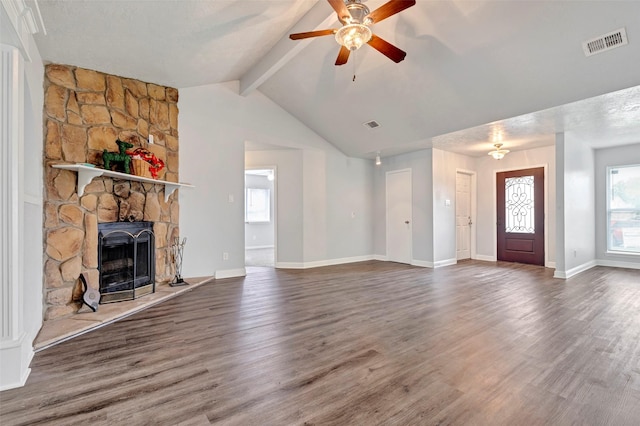 unfurnished living room featuring a stone fireplace, dark wood-type flooring, vaulted ceiling with beams, and ceiling fan