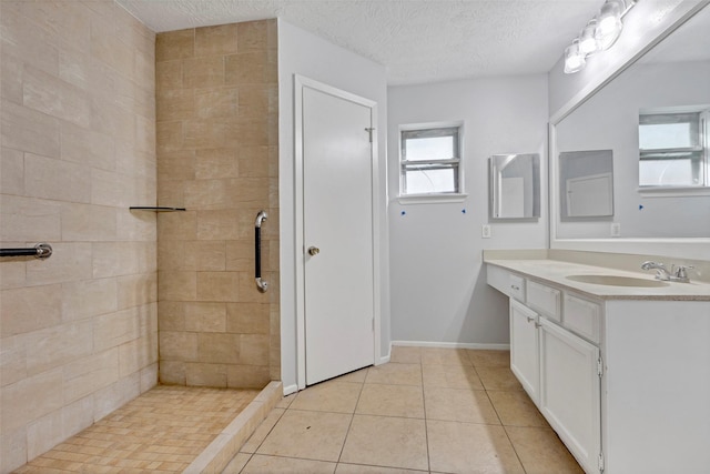 bathroom featuring tiled shower, vanity, tile patterned flooring, and a textured ceiling