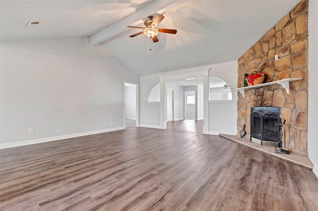 unfurnished living room with a stone fireplace, lofted ceiling with beams, ceiling fan, and wood finished floors