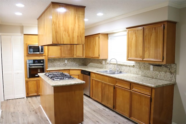 kitchen with sink, a kitchen island, stainless steel appliances, and light hardwood / wood-style floors