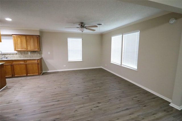 kitchen with dark hardwood / wood-style flooring, tasteful backsplash, ornamental molding, ceiling fan, and sink