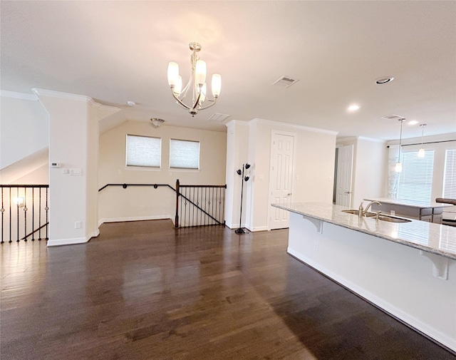 kitchen with a breakfast bar, sink, hanging light fixtures, dark hardwood / wood-style floors, and light stone counters