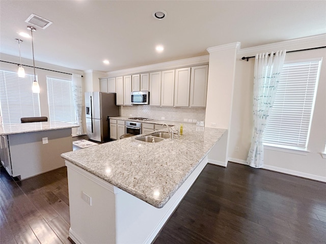 kitchen featuring pendant lighting, dark wood-type flooring, sink, kitchen peninsula, and stainless steel appliances