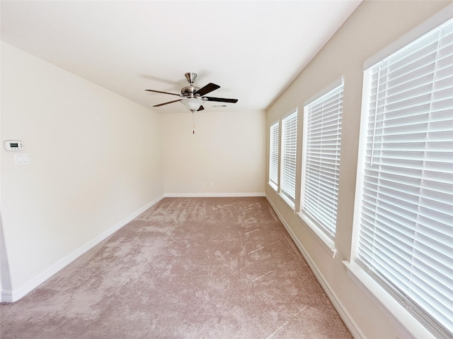 carpeted spare room featuring a wealth of natural light and ceiling fan