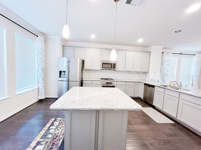 kitchen with decorative light fixtures, a wealth of natural light, light stone counters, and appliances with stainless steel finishes