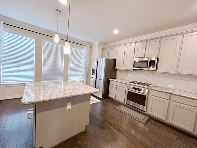 kitchen featuring dark wood-type flooring, crown molding, hanging light fixtures, light stone countertops, and appliances with stainless steel finishes