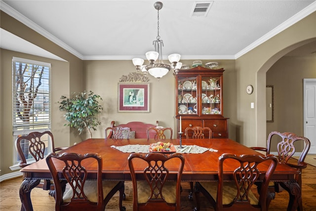 dining area featuring ornamental molding, wood-type flooring, and a notable chandelier