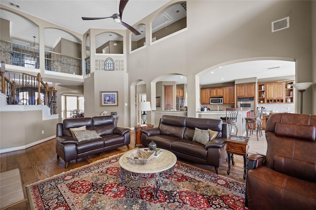 living room with a high ceiling, ceiling fan, and hardwood / wood-style floors